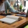 Person working on laptop and tablet with notebook open