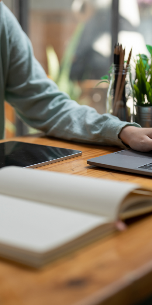 Person working on laptop and tablet with notebook open