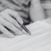 Hand holding a pen whilst reading a legal agreement