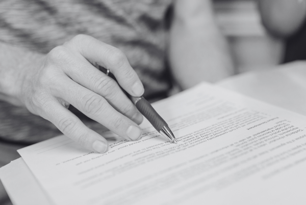 Hand holding a pen whilst reading a legal agreement