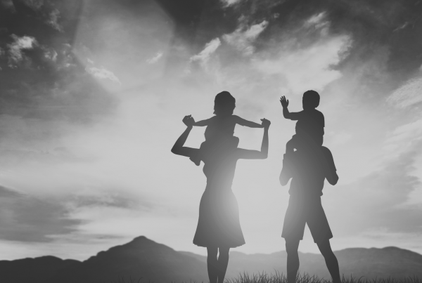 Parents carrying children on shoulders in field
