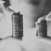 Hands holiding two different size stacks of one pound coins