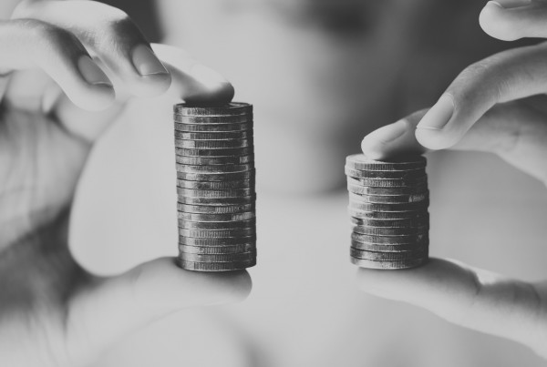 Hands holiding two different size stacks of one pound coins