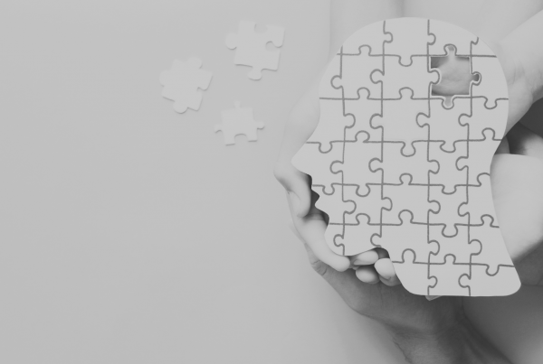 Head jigsaw puzzle being held by multiple hands