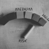 Low, medium, high risk gauge made out of wooden blocks with pointer on high risk