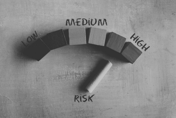 Low, medium, high risk gauge made out of wooden blocks with pointer on high risk