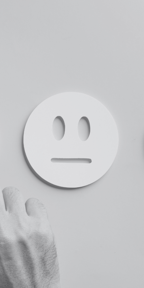 Three face cut outs in card with a hand pointing at the upset face
