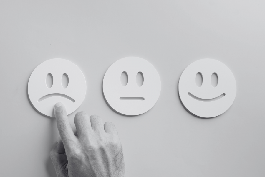 Three face cut outs in card with a hand pointing at the upset face