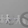 Line of paper cut people with stop sign over two of the people showing that they're excluded