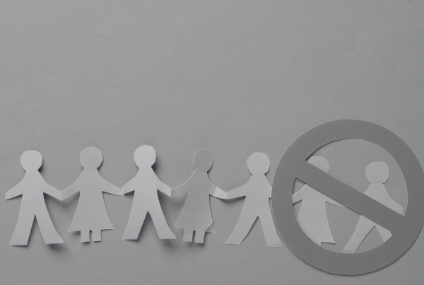 Line of paper cut people with stop sign over two of the people showing that they're excluded